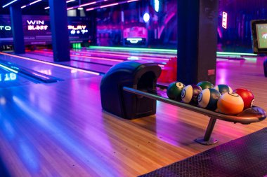 Top rafı ve dar sokaklar boyunca parlak kırmızı ve mavi ışıklandırmayla modern bowling iç mekanları eğlence ve eğlence ortamı yaratıyor..