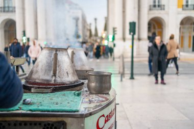Lizbon sokaklarında satılan kavrulmuş kestaneler Portekiz 'de satılmak üzere kavrulmuş fındıklarla birlikte bulanık arka planda duruyor.
