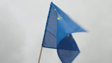 Altın yıldızlı Avrupa Birliği Bayrağı bulutlu gri gökyüzüne karşı rüzgarda dalgalanıyor