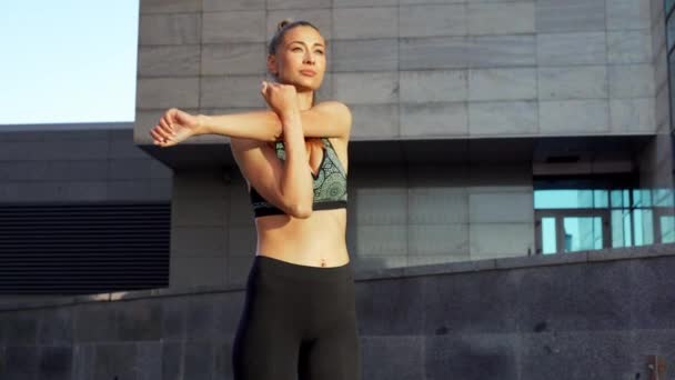 Pasująca Kobieta Rozgrzewa Ciało Przed Joggingiem Stojąc Pobliżu Budynku Sportowa — Wideo stockowe