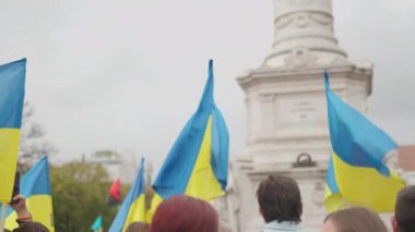 Ukrayna bayrağı taşıyan mavi sarı bayraklı kadın ve erkek Lizbon sokaklarında Ukrayna 'daki savaş ve Rus işgalini protesto ediyor. Avrupa kentinden Ukrayna 'ya destek