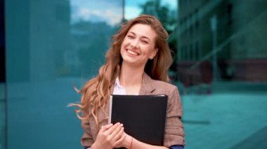 Modern ofis dışında başarıyı kutlarken uzun kahverengi saçlı, gülümseyen genç iş kadınının portresi. Profesyonel kadın yumruğunu sıkıp şehirde zaferin tadını çıkarıyor..
