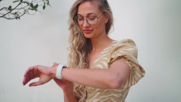 Gelukkige Vrouw Bril Die Tijd Controleert Polshorloge Zittend Tegen Een — Stockvideo