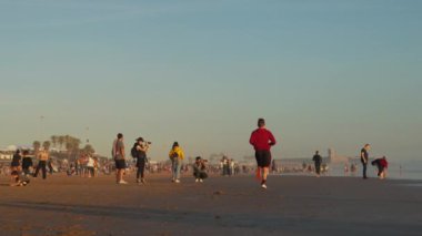 Carcavelos, Portekiz 18 Şubat 2024 atletik koşucu gün batımında Ocean Beach 'i işletiyor. Yaz tatilleri. Kumsalda yürüyen farklı insanlardan oluşan bir grup, sıcak havanın tadını çıkarın. 