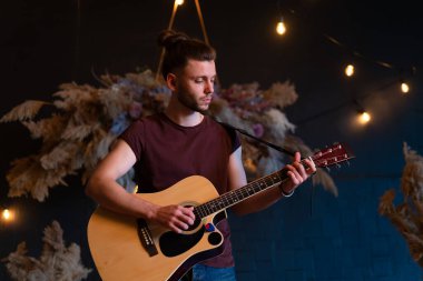 Erkek müzisyen akustik gitar çalıyor. Gitarist konserde klasik gitar çalıyor. Yakışıklı erkek gitarist özel bir parti veriyor. Uzun saçlı, orta boy.