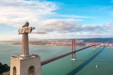 Portekizlerin başkenti Lizbon 'u ve Tagus Nehri' nin karşısındaki 25 de Abril Köprüsü 'nü gören Kral İsa' nın dev heykel mabedi etrafında uçan insansız hava aracı. Lizbon, Portekiz 'deki simgeler ve altyapı