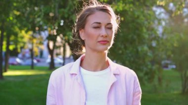 Parkta daha iyi görebilmek için gözlük takan bir kadın. Genç beyaz kadın gözlük takıyor. Görme yetisini arttırıyor ve mutlu bir şekilde gülümsüyor. Oftalmoloji sağlık hizmetleri tıp konsepti.