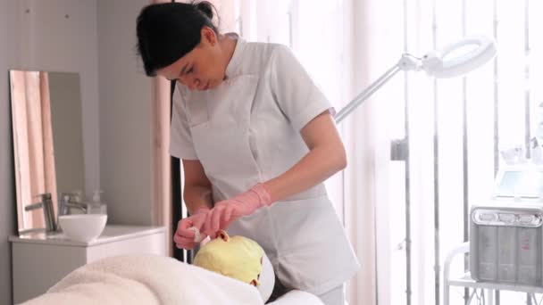 Vrouwelijke Professionele Cosmetoloog Uniform Van Toepassing Geel Alginaat Masker Het — Stockvideo