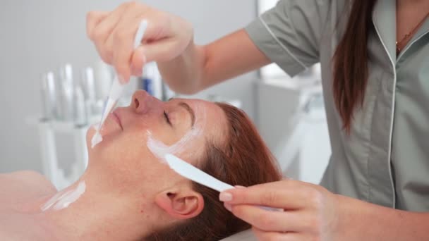 Professionelle Kosmetologie Kosmetikerin Wellness Salon Trägt Junge Frau Gesichtspeeling Maske — Stockvideo
