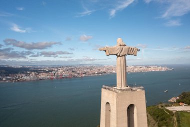 Kral İsa 'nın hava manzaralı anıtı. Almada şehri ve Tagus Riverin arka planına sahip görkemli manzara heykeli. Kuş bakışı Katolik anıtı ve şehri 