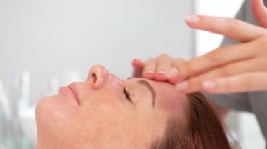 Kadın yüzüne masaj yapan masaj terapistinden yenilenen cilt bakımı prosedürü alıyor. Güzellik salonunda spa ve masaj. Güzellik salonunda yüz masajı.