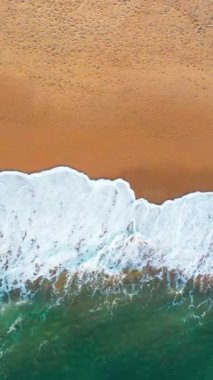 Kumlu sahil şeridindeki deniz dalgalarının insansız hava aracı görüntüsü. Dalgalar kıyı boyunca zarifçe koparken doğanın ritmi gelişiyor. Huzurlu ve büyüleyici sahil manzarası yaratıyor..