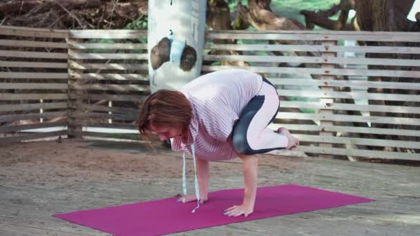 女人在松林的木地板上做瑜伽 中年妇女练习瑜伽姿势冥想慢动作 健康生活方式的概念 — 图库视频影像