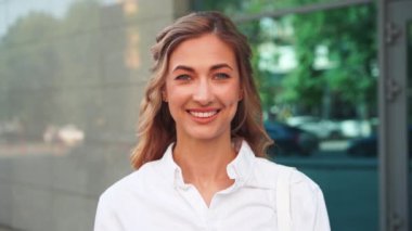 Ofis binası dışında başarılı bir iş kadını. Gündüz vakti gülümseyen ve kameraya bakan güzel bir bayan profesyonel..