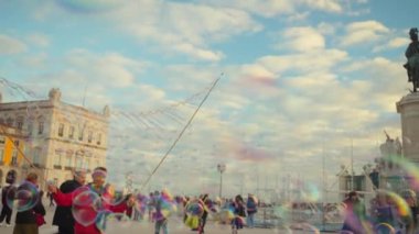 Portekiz, Lizbon 25 Aralık 2023 Çocuklar Lizbon 'daki Ticaret Meydanı' nda sabun köpüğü gösterisinin keyfini çıkarın. Çocuklar havada uçuşan baloncukları yakalamaya çalışıyor. 