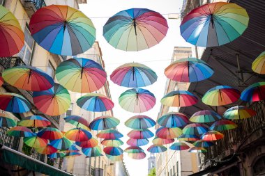 Renkli şemsiyeler caddeyi süslüyor, mavi gökyüzüne karşı canlı bir görüntü oluşturuyor. Birçok gökkuşağı şemsiyesi, özellikle Onur Ayı boyunca, festival sokak dekorasyonlarına katkıda bulunur..