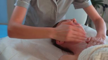 Kozmetik salonundaki kadınlara boyun masajı yapan masaj terapisti. Rahatlamış bayan müşteri, profesyonel güzellik uzmanları tarafından şımartılıyor.. 