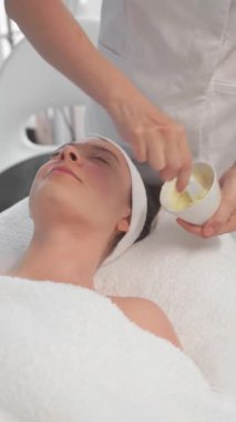 Güzellik uzmanı kremalı maddeyi kaseye karıştırıyor. Kozmetik uzmanı güzellik salonunda yatan rahat kadın için aljinat kremi hazırlıyor. Spa ve güzellik tedavi kavramı.