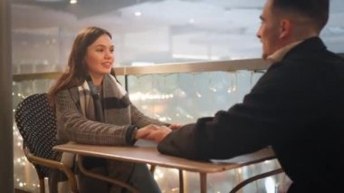Noel gecesi teras restoranında el ele tutuşan romantik bir çift. Sevecen erkek ve kadın festival döneminde kaliteli zaman geçiriyorlar.. 
