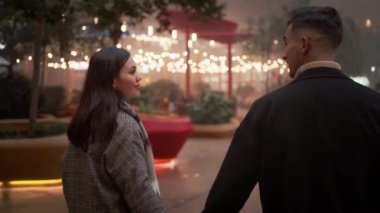 Noel gecesi şehir caddesinde yürürken el ele tutuşup öpüşen romantik bir çift. Sevecen genç bir adam ve kadının birbirlerine bakışları.. 