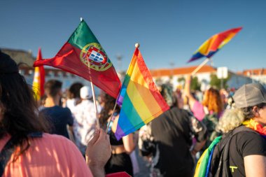 LGBTQ çalışanı Pride Parade 'de Portekiz bayrakları ve gökkuşağı taşıyor. LGBTQAI hakları için mücadele eden kalabalık. Destek, saygı, gurur, LGBTQAI insanları mavi gökyüzü altında.