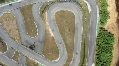 İnsansız hava aracı Go-Kart 'ları yakalıyor. En üst hava perspektifinden dönüş pistlerinde ilerliyorlar. Kırsalda gündüz vakti yarışlara uzak bir bakış açısı. 