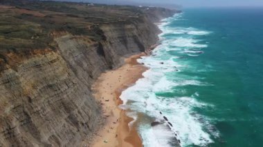 Magoito Sahili 'ndeki resimli deniz manzarası ve kayalık uçurumların insansız hava aracı görüntüleri. Gündüz vakti Portekiz, Sintra 'daki manzaralı bir yerden. 