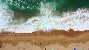 Magoito Sahili 'ndeki ıslak kumlu sahile düşen deniz dalgalarını gösteren drone görüntüsü. Portekiz 'in Sintra kentindeki ünlü varış yerindeki tanınmayan insanlardan.. 