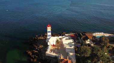 Güneşli bir günde Santa Marta Deniz Feneri 'nin deniz manzaralı insansız hava aracı görüntüleri. Yaz mevsiminde marina kıyısındaki kayalık sahilin yukarısından. 