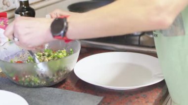 Ekin kadın elleri mutfak tezgahında taze salata servisi yapıyor. İsimsiz bir kadın evde öğle yemeği hazırlıyor.. 