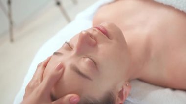 Ekin masajı terapisti kozmetoloji kliniğinde kadınların alnına masaj yapıyor. Rahatlamış bayan müşteri profesyonel güzellik uzmanı tarafından kaplıcada şımartılıyor.. 