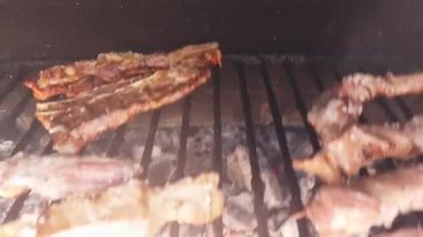 Pişmeye başlayan domuz kaburgalarının yakından görüntüsü, kızgın kömür kaburgaları üzerinde cızırdarken hafif yanmış bir dış görünüşü gösteriyor. Kahverengileşmeye ve lezzetlerini bırakmaya başlıyorlar.