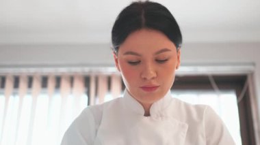 Masaj terapisti kozmetoloji kliniğindeki isimsiz müşteriye masaj yapıyor. Güzel, profesyonel güzellik uzmanının salonda beyaz üniforma giydiği bir fotoğraf.. 