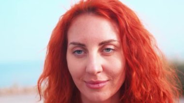 Güneşli bir günde açık gökyüzüne karşı mutlu kızıl saçlı sporcu kadın. Açık havada mavi gözlü sağlıklı genç bir kadının portresini büyüt.. 