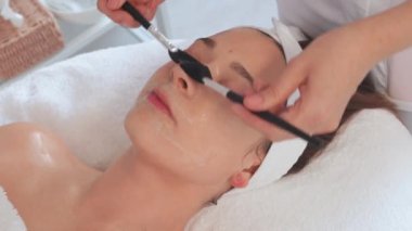 Profesyonel kozmetoloji: Ekin masajı terapisti kuaförde fırçalı kadınlara yüz maskesi uyguluyor. Rahatlamış kadın müşteriler spa 'da isimsiz güzellik uzmanları tarafından şımartılıyor.. 