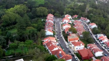 Sintra Portekiz 'in banliyö bölgesindeki insansız hava aracı görüntüleri bir katlı ve yemyeşil ormanın yakınında iki katlı evler gösteriyor. Spor alanı görünür, toplumsal atmosfer ve manzaranın vurgulandığı alanlar