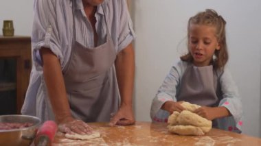 Evde isimsiz bir büyükannenin yardımıyla hamur işi yoğuran tatlı bir kız. Küçük bayan çocuk, son sınıftaki kadından yemek pişirmeyi öğreniyor. 