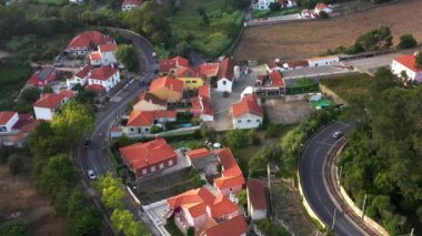 Portekiz, Sintra 'daki banliyö bölgesinden geçen dolambaçlı yolun büyüleyici görüntüsü. İnsansız hava aracı, konutların virajlarında ve dönüşlerinde arabaların sakin atmosferini yakalıyor