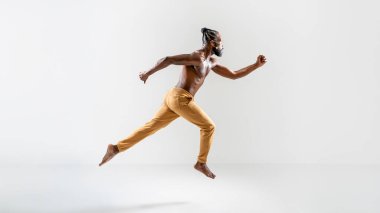 Gri arka planda zıplayan kararsız eşcinsel model. Güçlü genç adamın tüm vücudu düz bir stüdyoda havada.. 