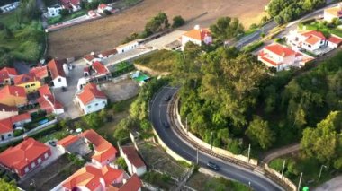 Portekiz, Sintra 'daki yerleşim bölgesinden geçen dolambaçlı yolların hava aracı görüntüleri. Huzurlu banliyöler ağaçlık cadde boyunca giden arabalarla gösteriliyor