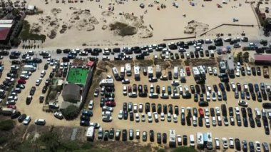 İnsansız hava aracı popüler bir plajın yanında içi araba dolu bir otoparkı yakalıyor. Görüntü, turizm sezonunda canlı atmosferi ve plaj erişimine olan yüksek talebi vurguluyor.