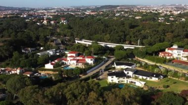 Uçsuz bucaksız yemyeşil arazinin güneşli bir günde şehirde inşa ve köprü kuran hava aracı görüntüleri. 