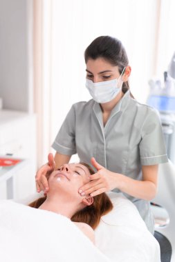 Güzellik salonunda kozmetik uzmanı kadınlara masaj yapıyor. Rahatlamış bayan müşteri güzellik uzmanları tarafından şımartılıyor.. 