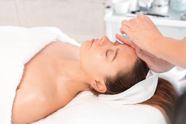 Anonim kozmetik uzmanları güzellik salonunda kadınlara masaj yapıyor. Rahatlamış bayan müşteri güzellik uzmanları tarafından şımartılıyor.. 