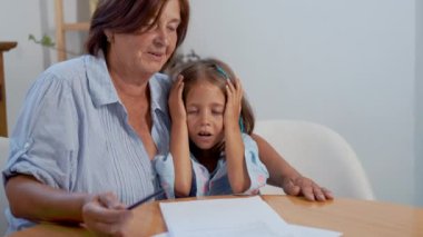 Büyükannesi torununa okul ödevleriyle bir masada bakıyor. Çocuk hayal kırıklığı ve belirsizlik belirtileri gösterirken, büyük olan sabırla ve nazikçe kavramları açıklıyor..