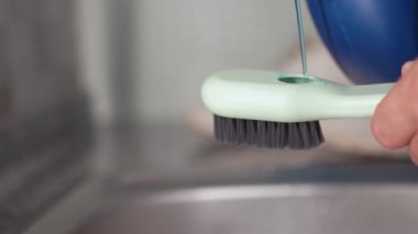 Ayakkabı temizleme fırçasını temizleme işlemi ve ayakkabı bakımında kullanılan aletleri vurgulamadan önce deterjan toplarken yakın çekim görüntüsü
