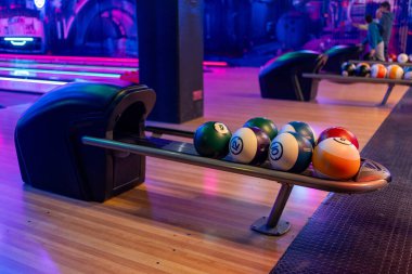 Top rafı ve ara sokaklar boyunca neon kırmızı ve mavi ışıklandırmalı modern bowling iç mekanı eğlence ve eğlence ortamı yaratıyor..