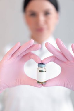 Klinikte iğne yapmak için elinde boş bir ilaç şişesi tutan isimsiz bir kadın dermatolog. Genç kozmetoloji terapisti güzellik salonunda pembe eldivenler giyiyor.. 