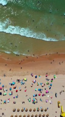 Havadan çekilen dikey görüntüler kumlu kumsalda yazın tadını çıkaran insanlarla doluydu. Bazıları güneşlenirken diğerleri suda yüzüyor. Video, plaj tatillerinin özünü yakalıyor.