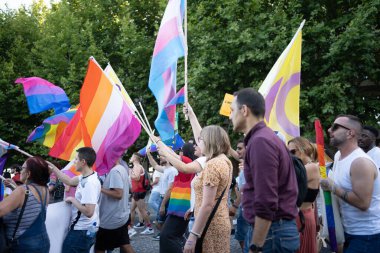 Şehirdeki gay onur yürüyüşünde gökkuşağı bayraklı bir grup homoseksüel insan. Erkekler ve kadınlar güneşli bir günde LGBTQ haklarını kutluyorlar. 